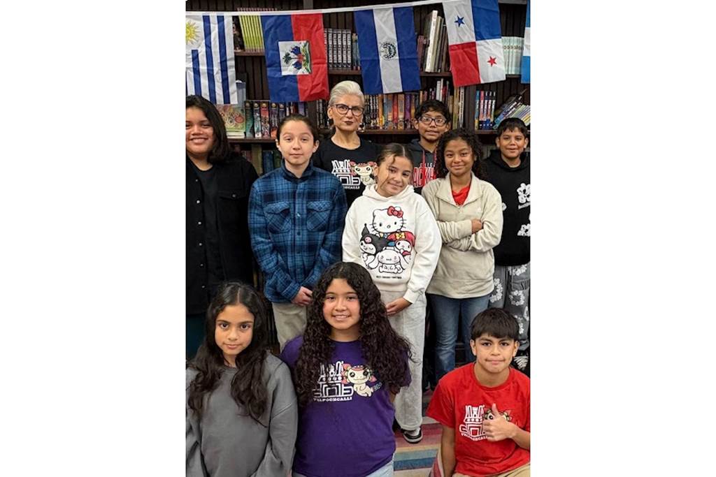 Principal Gabriela Núñez smiling while posing with a group of elementary students at Telpochcalli Elementary School.