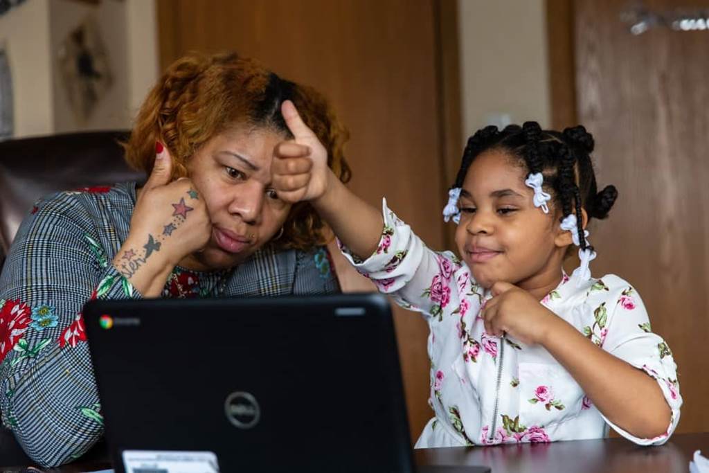 Mother and daughter using a laptop to attend a virtual class.