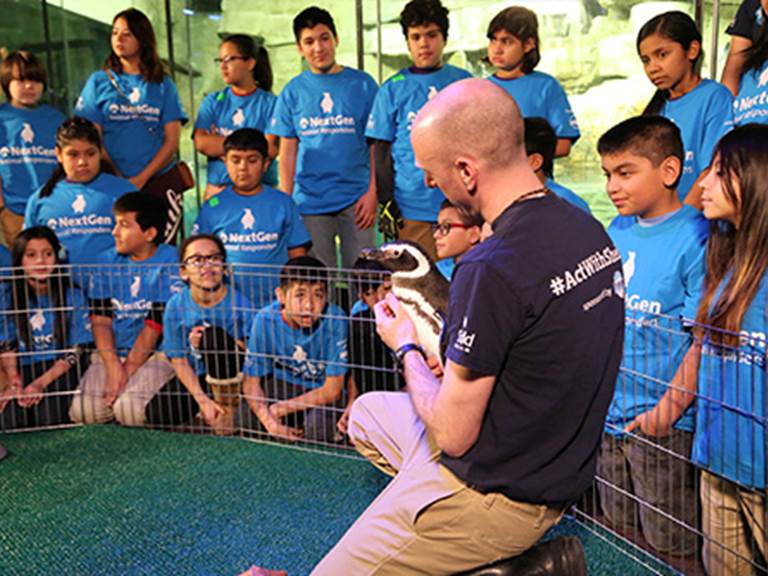 Students watching as man holds a snake