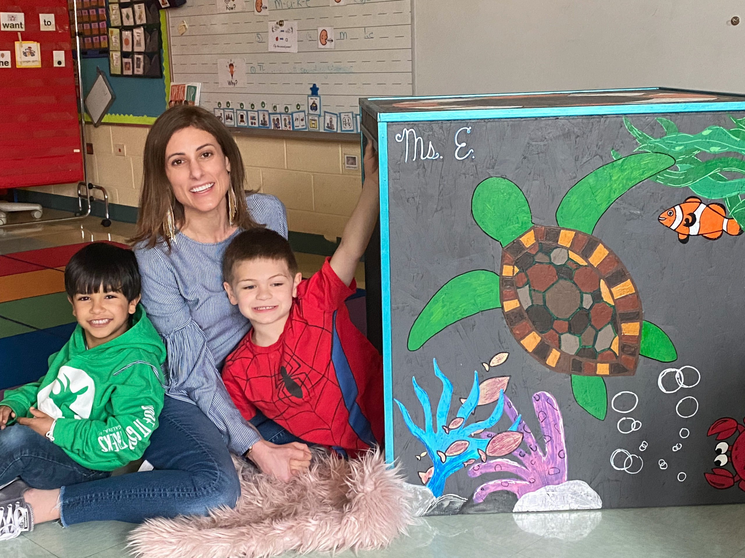 Teacher with two students, showing off a sea turtle drawing