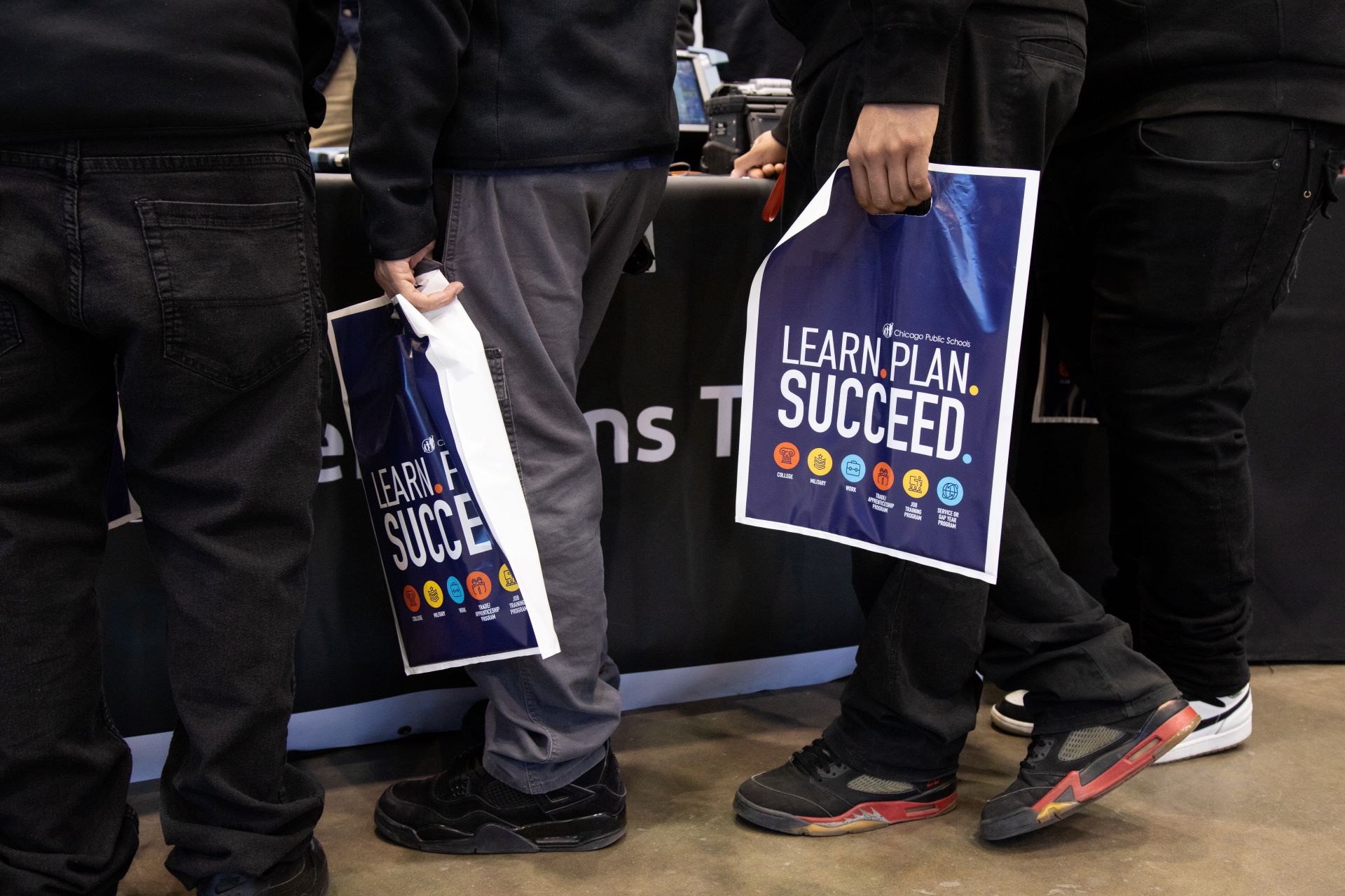 students holding learn plan succeed bags