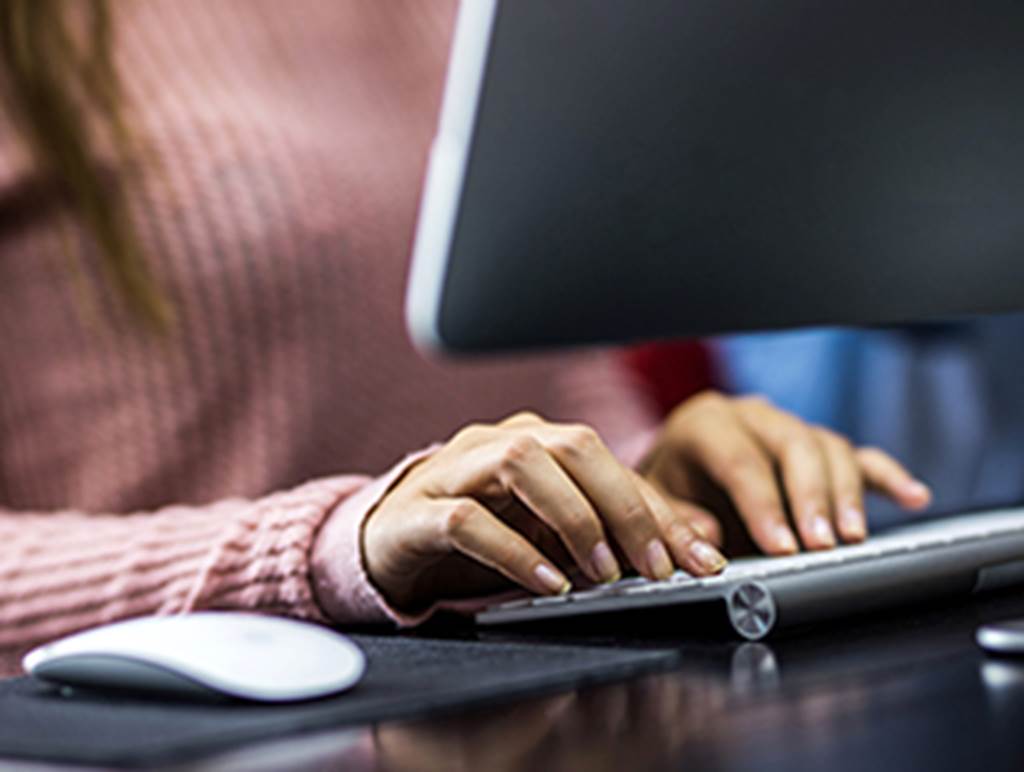 Two hands typing on a computer keyboard