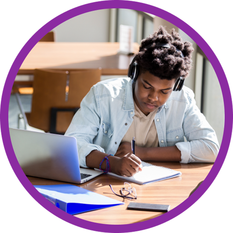 Student taking notes on a notepad while listening to a online lecture