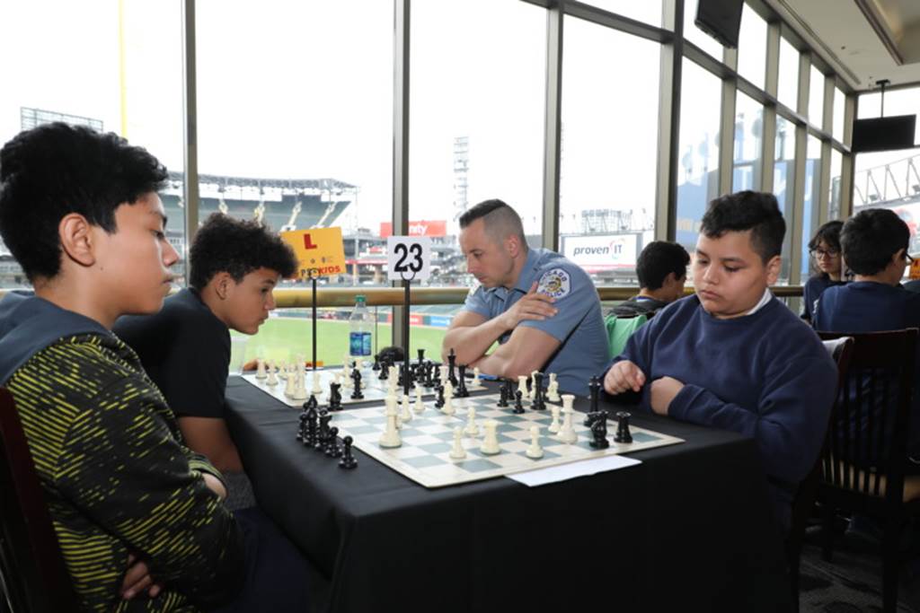 Students playing chess with police officers