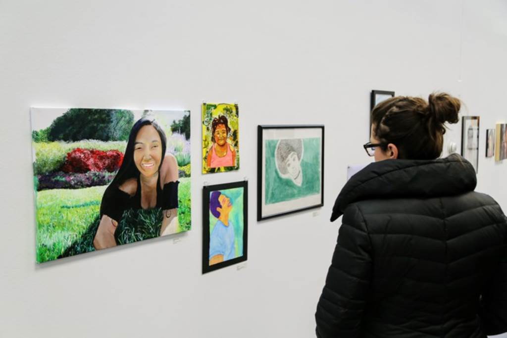 A woman stares at student artwork