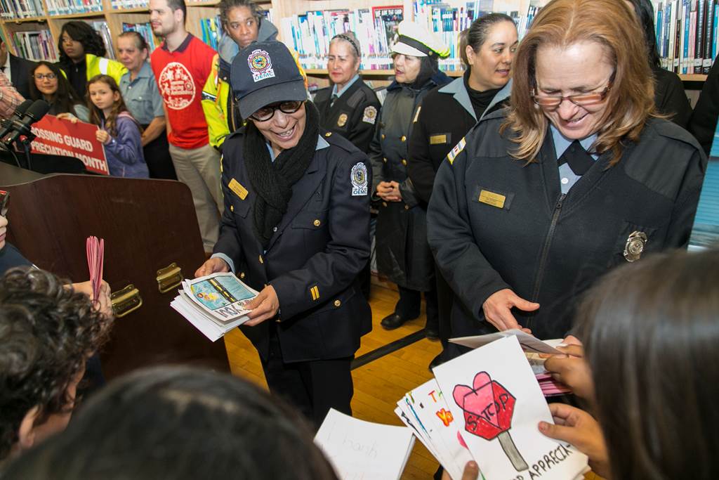 Students hand drawings to crossing guards