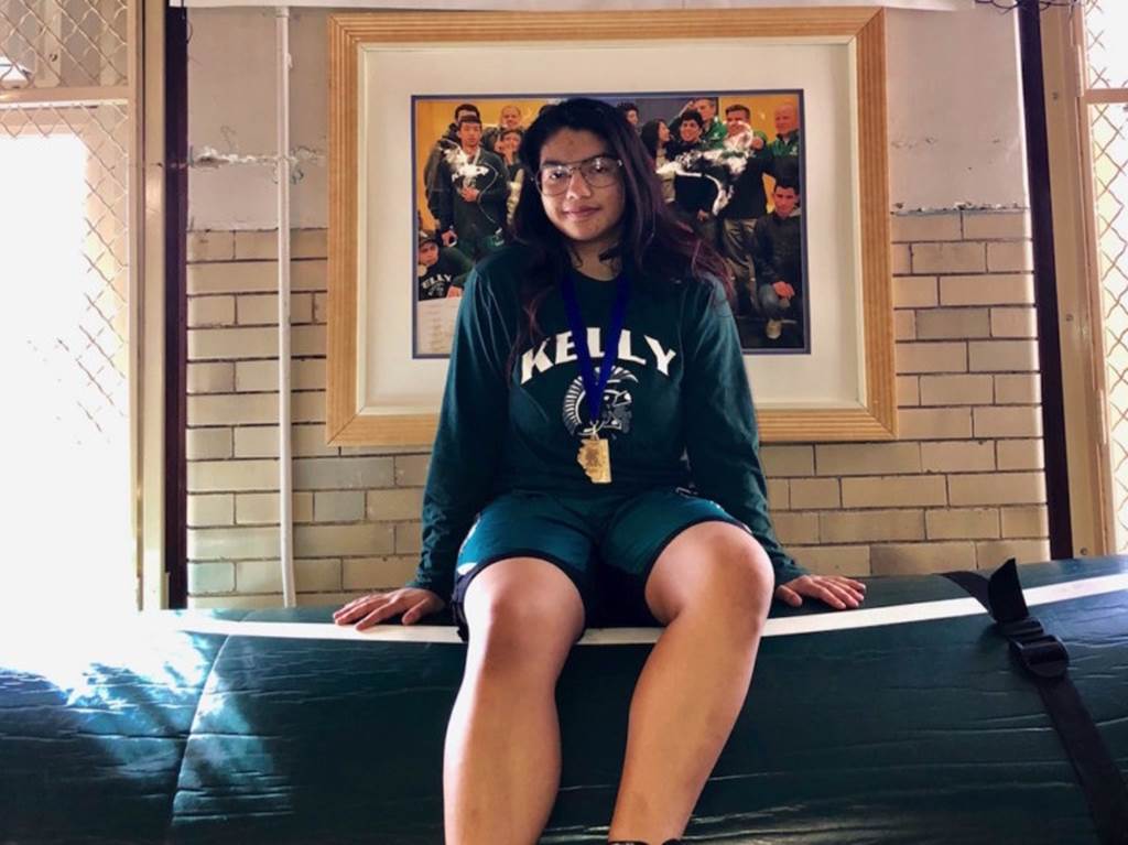 Mayra Morales sits in front of a portrait of her team mates