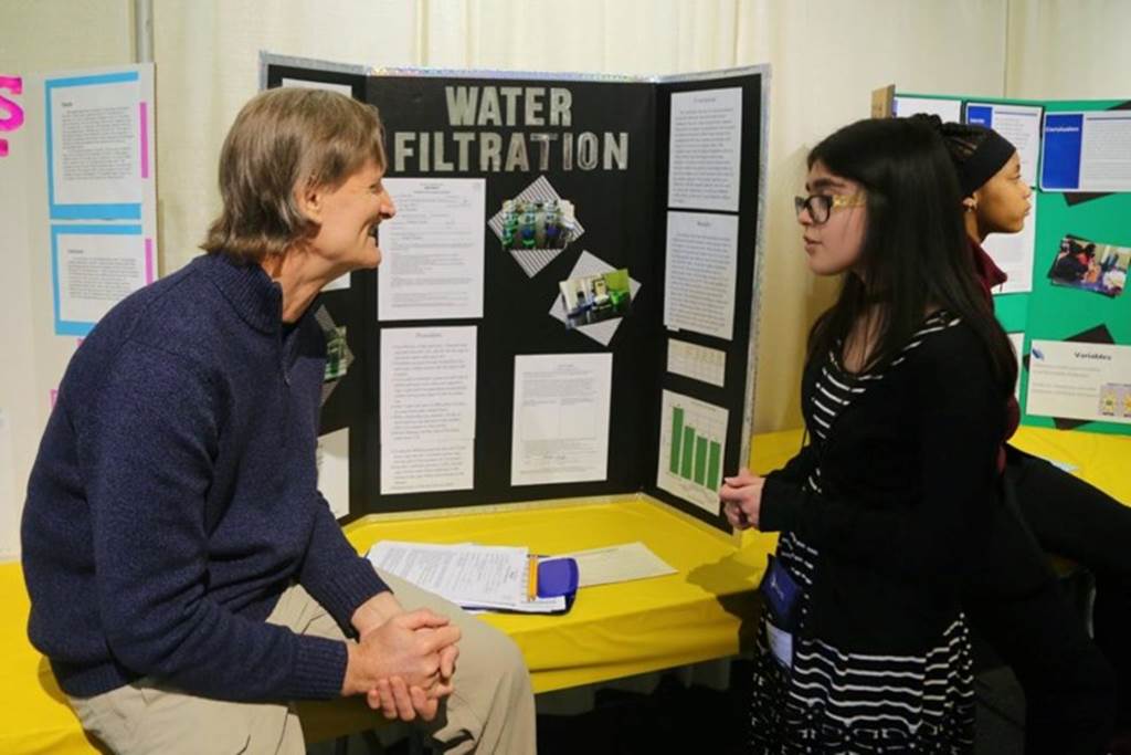 A student presents her project to a judge