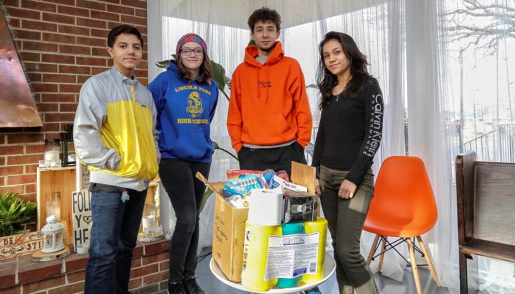 Four students stand behind a box of supplies