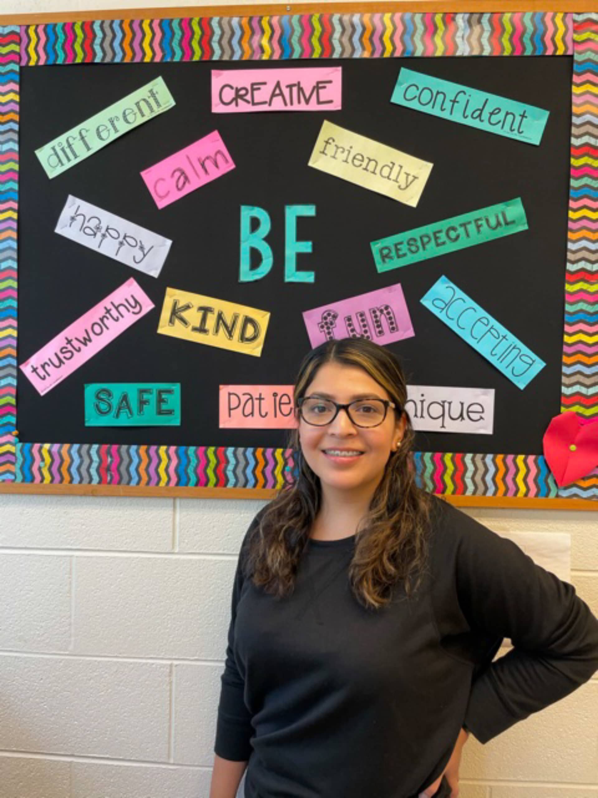 Ms. Lissette Flores standing in front of a board of positive quotes