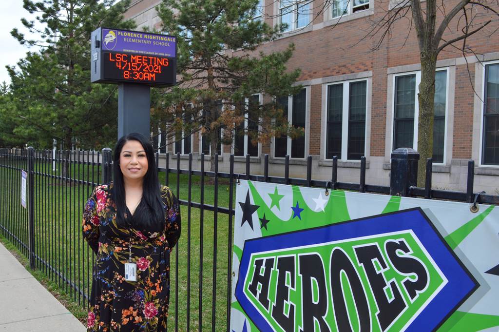 Ms. Michelle Soto standing next to a sign that says heros