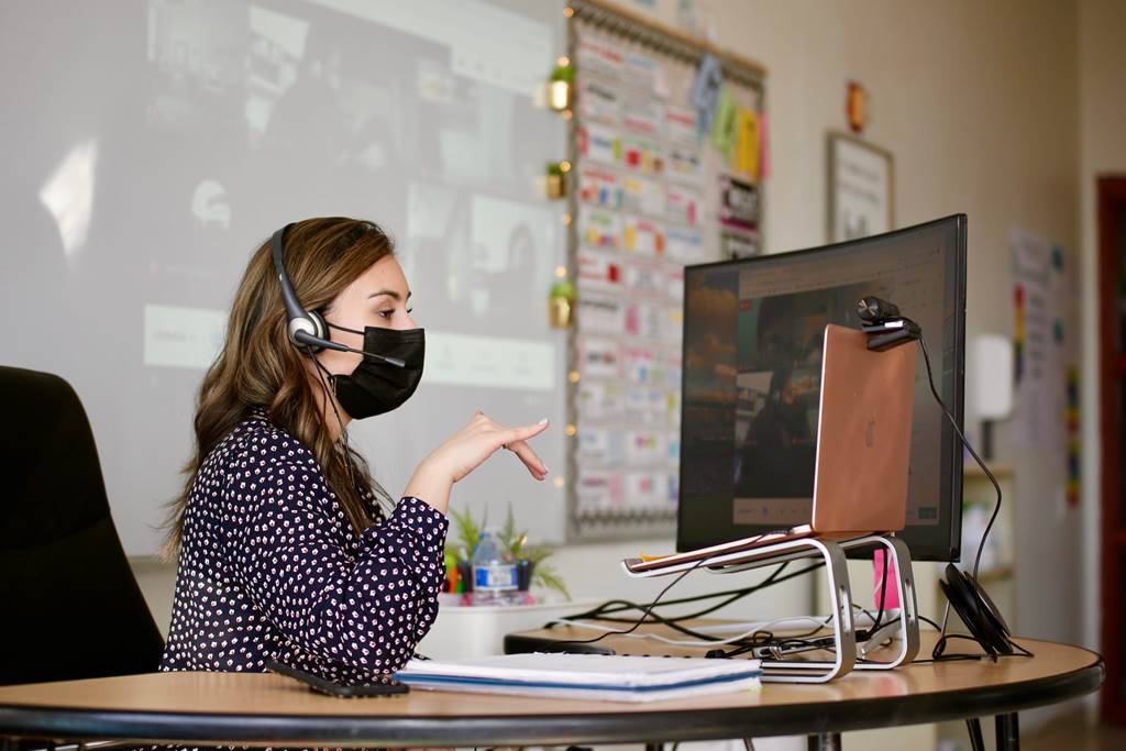 A teacher sitting at her desk while talking to students over zoom